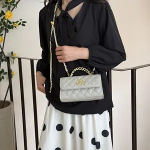 Detailed view of the stylish quilted chain shoulder bag, highlighting the metal handle and texture.