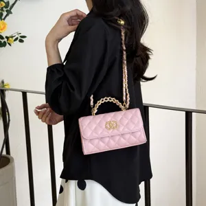 Detailed shot of pink quilted crossbody bag with gold chain strap and stylish clasp design.