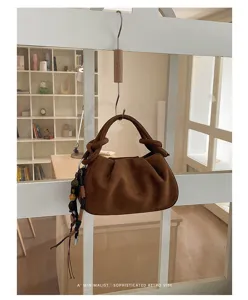 Brown suede hobo shoulder bag with knotted handle and retro minimalist dumpling bag design.