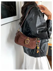 Close-up view of the vintage brown suede underarm bag showcasing its metallic buckle.