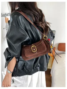 Detailed view of brown suede shoulder bag with metal buckle and charming pendant design.