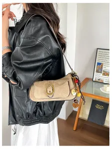 Vintage suede shoulder bag for women, patchwork design with metal buckle and chic charms.