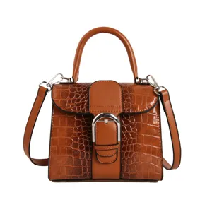 Close-up detail of the brown crocodile pattern leather handbag with metallic D-shaped buckle.