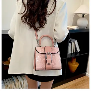 Detail shot of stylish pink crocodile pattern handbag with color-block design and metal buckle.