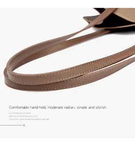 Détail de poignée de sac à main en cuir marron avec coutures fines et design confortable.