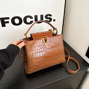 Stylish brown crocodile embossed top handle bag with gold V logo for women daily commuting.