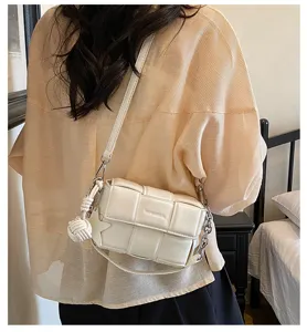 Détail du sac à bandoulière tressé blanc avec chaîne tendance et pendentif élégant.