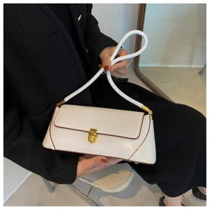 Detailed view of white vintage baguette shoulder bag with gold lock and brown piping.