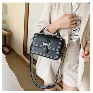 Close-up detail of the black crossbody bag showing its contrast white stitching and metal lock.