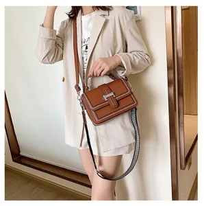 Detailed shot of brown leather crossbody bag featuring metal H clasp, top handle and wide strap.