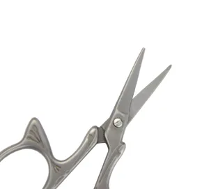 Vintage stainless steel embroidery scissors detail close-up, titanium-plated finish craft tool.