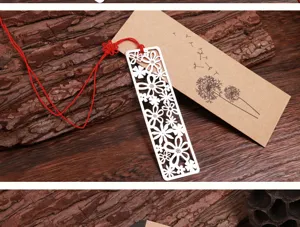 Marque-page en métal ajouré motif floral avec gland rouge et carte en papier kraft.