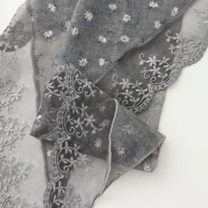 Close up detail of grey lace triangle scarf with floral pattern and delicate scalloped lace edge.