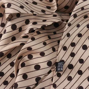 Gros plan sur un foulard en soie à pois chic, montrant une texture lisse et son étiquette.