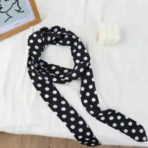 Vue détaillée d'un foulard en soie noire à pois blancs, accessoire de cou élégant et fin.