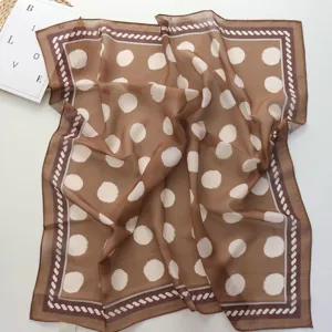 Vue de détail d'un carré de foulard marron à pois, matière légère et douce avec bordure.