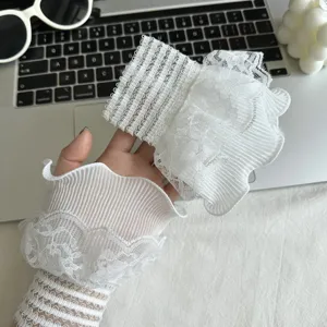 Detailaufnahme weißer Spitzen-Handgelenkmanschetten, süßes florales Design für stilvolle Mode.