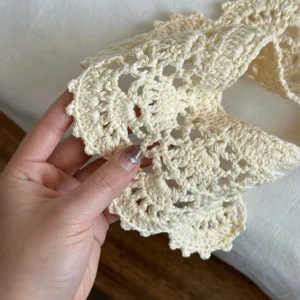 Primo piano di colletto finto in pizzo all'uncinetto beige, mini scialle vintage.