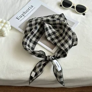 Detalle de pañuelo triangular de lino a cuadros en blanco y negro, accesorio chic.