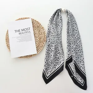Detalle de un pañuelo twilly con estampado de leopardo y hebilla magnética de perla.