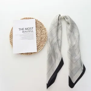 Pañuelo de seda estrecho con estampado geométrico en blanco y negro y hebilla magnética de perlas.