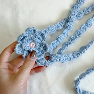 Nahaufnahme des handgefertigten blauen Häkelblumenschals mit feiner und zarter Strickstruktur.