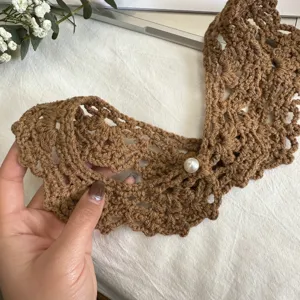 Detailed shot of handmade brown crochet fake collar featuring a pearl button decor.