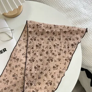 Primo piano di una sciarpa triangolare floreale marrone con bordi arrotolati scuri.