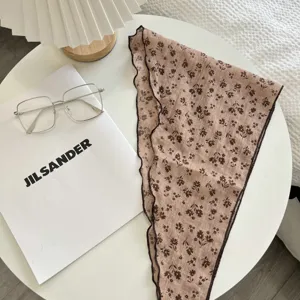 Vista dettagliata di un foulard triangolare vintage a fiori marroni con bordo delicato.