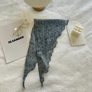 Vista dettagliata del fazzoletto triangolare floreale grigio con bordi ondulati e delicato motivo.