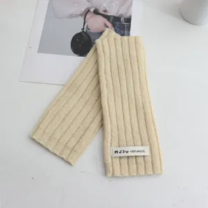 Detailed view of beige ribbed knit wool fingerless gloves with brand label, cozy warm wrist.