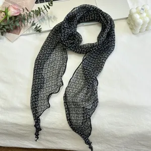 Detailopname van zwarte bloemendruksjaal voor dames met elegante 3D bloemenknoopstructuur.