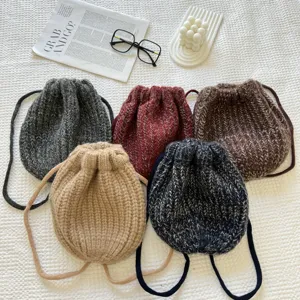 Detailansicht gemütlicher, gestrickter Kordeltaschen in verschiedenen Herbstfarben mit Trägern.