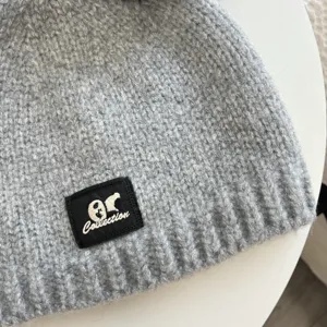 Detail shot of a grey knit beanie hat featuring a chic patch, cozy winter headwear for daily wear.