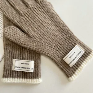 Detailed view of cozy warm knitted gloves featuring ribbed cuffs and stitched brand labels.