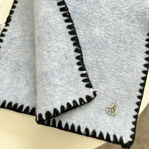 Light blue knit scarf with black locked edges and cute silver heart charm detail cozy winter.