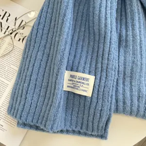 Detail des blauen Strick-Winterschals mit gemütlicher Rippstruktur und Markenlabel.