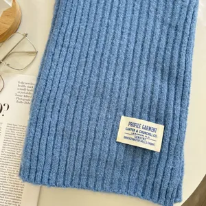 Detailaufnahme eines kuscheligen blauen Rippstrick-Winterschals mit stylischem Webetikett.