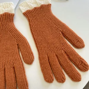 Detail view of winter warm knit gloves in rust orange with ribbed white cuffs, cozy touch design.
