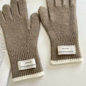 Detailed shot of brown knitted gloves with white cuffs and brand tags for winter warmth.