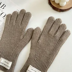 Close-up detail of brown knit gloves featuring cozy ribbed texture and cute cuff label design.
