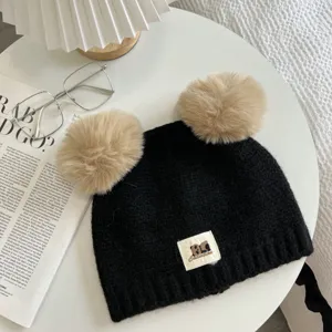 Cute double pom pom black knit beanie detail, soft winter warm cap with plush balls.