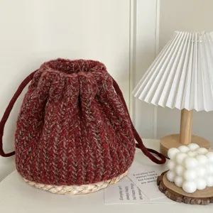 Nahaufnahme einer gemütlichen dunkelroten Strick-Kordelzugtasche mit geflochtenem Boden.