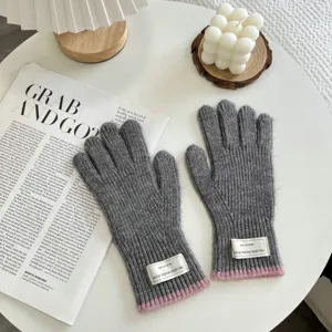 Detail view of warm grey knit gloves featuring pink cuffs and chic labels for winter daily wear.