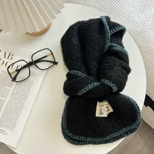 Detailed close-up view of black cozy knitted scarf featuring stylish blue edge design.