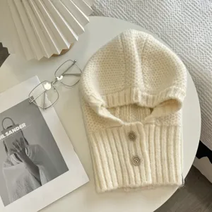 Nahaufnahme Detail der kuscheligen Strick-Balaclava Kapuzenmütze in Creme mit Knöpfen.