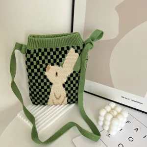 Groen-zwarte gebreide crossbodytas met schattig wit konijnenpatroon, gedetailleerde weergave.