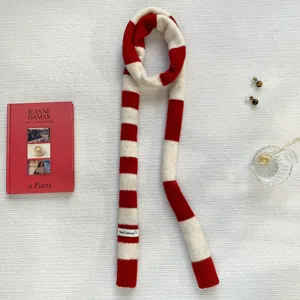 Detail view of a red and white striped knitted scarf with a small label, soft winter accessory.