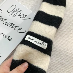 Black and white striped knitted narrow scarf detail shot, cozy texture and chic style.