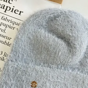 Close-up detail of grey fuzzy knitted beanie hat with metallic gold button accent winter warm